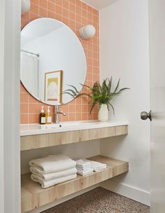 a bathroom with a sink, mirror and towels on the shelf in front of it