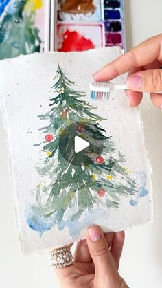 someone is painting a christmas tree with watercolors