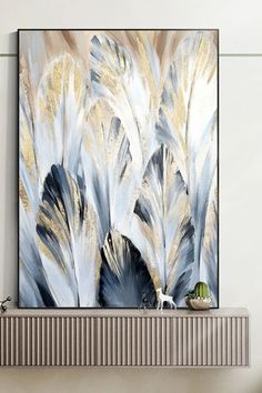 an abstract painting with white and blue feathers on a wall above a fireplace mantel