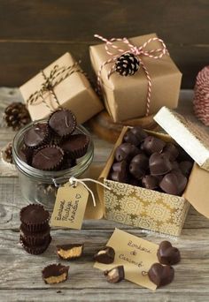 some chocolates are sitting in a box on a wooden table with tags around them