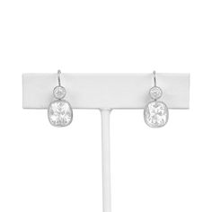 a pair of earrings with clear stones on a white display stand in front of a white background