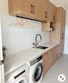 a washer and dryer in a kitchen with wooden cabinets above the counter top