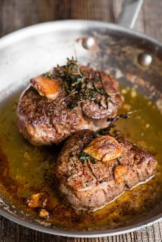 two steaks are cooking in a pan on the table