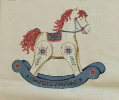 an embroidered rocking horse with red manes and flowers on it's body is shown