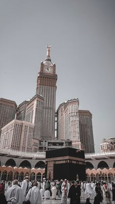 a group of people standing in front of a tall building with a clock on it