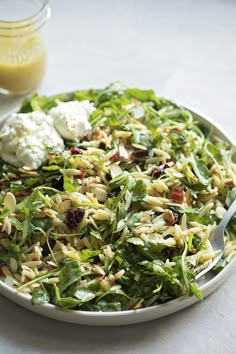 a white plate topped with salad next to a jar of dressing