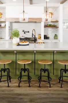 three stools sit in front of an island with green cabinets and white countertops