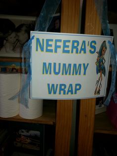 a sign that says nefera's mommy wrap hanging on a shelf in a store