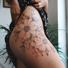 a woman's thigh with flowers on it and her leg in the foreground