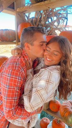 a man and woman kissing in front of pumpkins