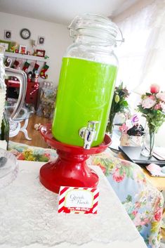 a green drink in a jar sitting on top of a red stand