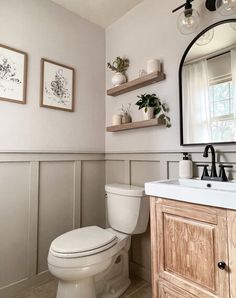 a white toilet sitting next to a sink in a bathroom under a large framed mirror