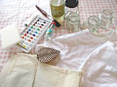 the contents of a crafting kit laid out on a checkered tablecloth with bottles and jars