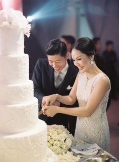 a newly married couple cutting their wedding cake