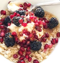 a bowl filled with oatmeal topped with berries and blackberries next to a spoon