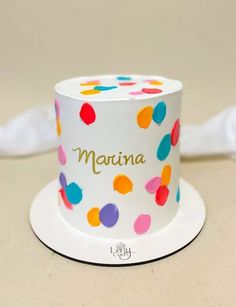 a white cake with multicolored polka dots on it's top and name