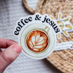 someone holding up a sticker that says coffee and jesus on it with a cup of coffee in the background