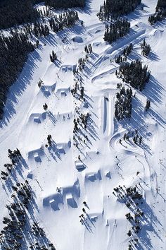 an aerial view of a snow covered ski slope with trees in the foreground and houses on the other side