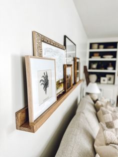 a living room filled with furniture and framed pictures on the wall next to a couch