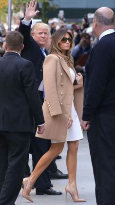 the first lady waves as she walks down the street with her hand in the air