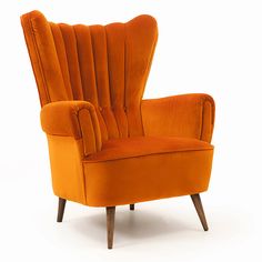 an orange velvet wingback chair with wooden legs and foot rests against a white background