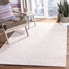 a living room area with a chair, rug and potted plant in the corner