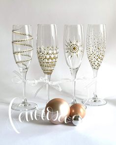 four wine glasses with gold and white decorations on them, one is for the holiday season