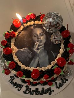 a birthday cake with a photo of a woman on it and candles in the background