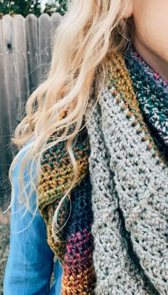 a woman with blonde hair wearing a multicolored crocheted scarf and jeans