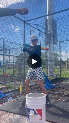 a young boy swinging a baseball bat on top of a batting cage at a park