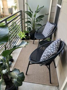 two black chairs sitting on top of a balcony next to plants