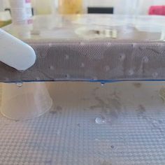 a mattress is sitting on top of a table with plastic cups and bottles around it