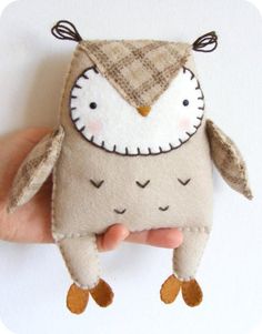 a hand holding a small stuffed animal with an owl on it's face and eyes