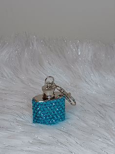 a blue bracelet is sitting on top of a white fur covered surface with a keychain attached to it