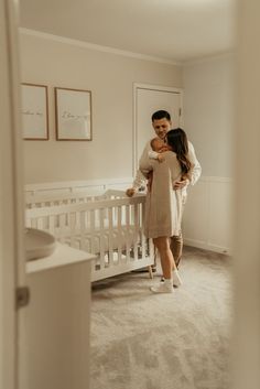 a man and woman standing next to each other in a room with a crib