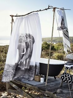 an elephant shower curtain is hanging on the side of a bathtub in front of some rocks