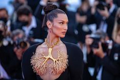 a woman in a black dress with a tree on it's chest and gold necklace