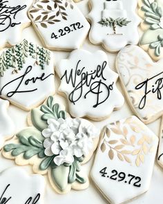 decorated cookies with wedding date names and flowers are displayed on a white tablecloth that is laid out in the shape of hexagonicals