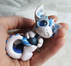 a hand holding a small toy with blue eyes and an animal on it's back