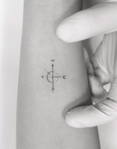 a small compass tattoo on the left inner arm, and an arrow in the middle