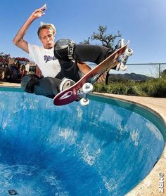 a man riding a skateboard up the side of a swimming pool