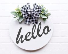 a white sign that says hello on it with a bow hanging from the front door