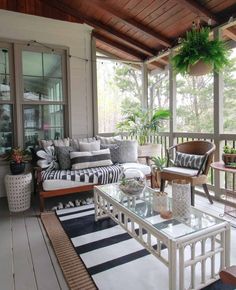 a living room filled with furniture on top of a hard wood floored porch covered in windows