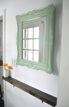 a mirror hanging on the wall above a shelf