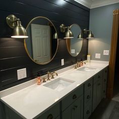 a bathroom with two sinks and three mirrors on the wall above them, along with lights