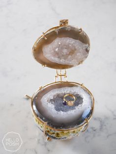 the inside of an open jewelry box on a marble counter top with a gold ring in it