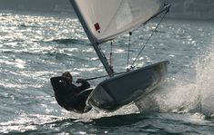 a man riding a sailboat on top of the ocean next to a boat in the water