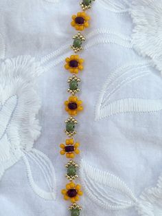 a beaded bracelet with flowers and beads on it's side, sitting on a white cloth