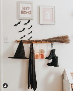 halloween decorations hang on the wall above boots and brooms in a room with white walls