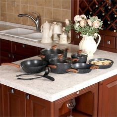 pots and pans are sitting on the kitchen counter next to a vase with flowers